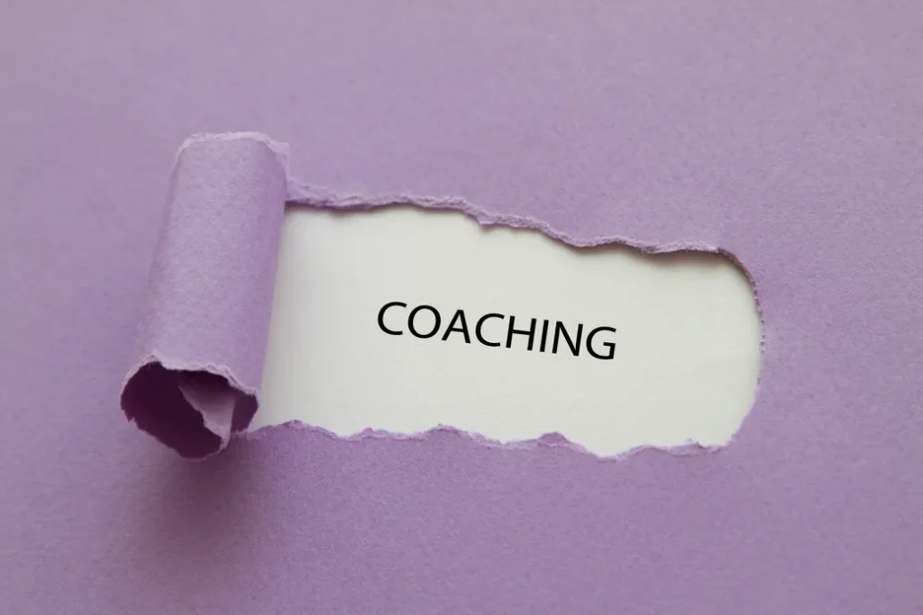Paper ripped to reveal the word COACHING